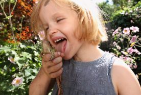 Close up of a girl pretending to lick the back of a frog