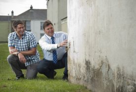 Two researchers inspect an exterior wall
