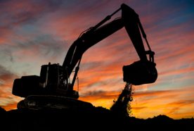 silhouette of a large digger extracting soil from a mine