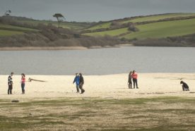 People in distance walking on beach with lake in the bakground