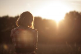 gril facing away from camera with sunset and lens flare