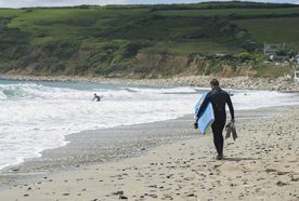 A bodyboarder walks towards the sea for a surf