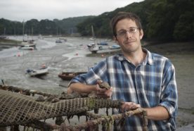 Nick Boase holds a muddy oyster at an estuary in Cornwall