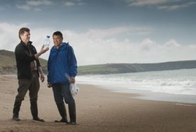 researchers examine a water sample at the seashore