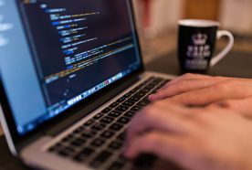 A close up of some hands typing code on a laptop