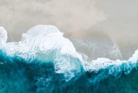 An aerial view of a blue ocean lapping onto the sand