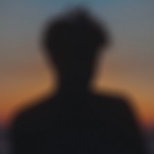 A silhouette of head and shoulders against an orange sky
