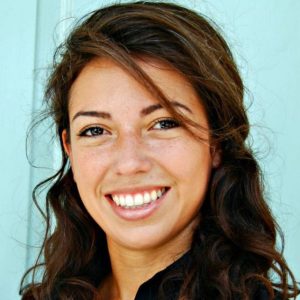 Miriam smiles for the camera against a blue background