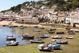 A sunny harbour in cornwall with boats on the sand