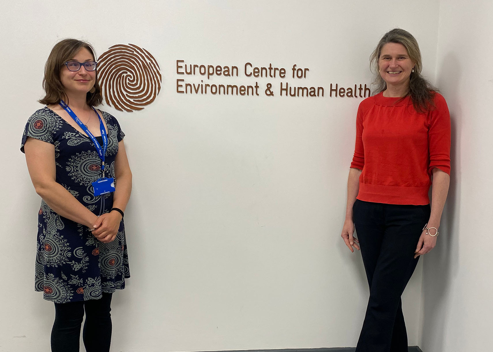 Jo Garrett and Jayne Kirkham MP stand either side of the European Centre's wooden logo, with a fingerprint swirl.