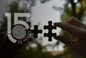 A pair of hands hold two jigsaw pieces up to the sky with a large 15yr logo overlaid